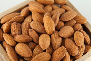 Wooden bowl with healthy dried fruit almonds; Photo on white background.
