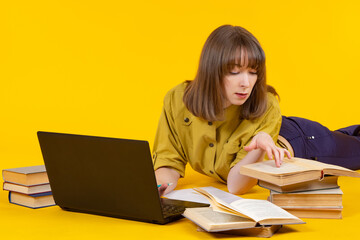Woman next to books and laptop. She studies books while lying down. Girl studies something from books. Woman preparing for lecture. Girl student prepares lecture. Concept student prepares her thesis