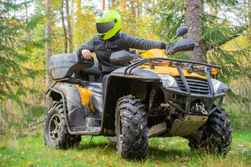 Man on a quad bike in forest. He drive through forest on ATV. Man on a yellow ATV. Concept -...