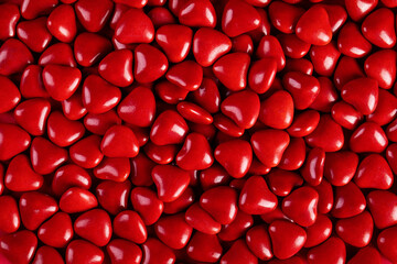 Top view of red heart-shaped candies in a container under the lights