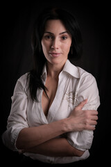 Portrait of beautiful mature brunette woman dressed in white shirt isolated on black background, copy space