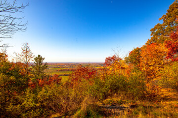 Beautiful fall colours with a view of farmland below. Mackenzie King Estate, Gatineau Park, Quebec, Canada