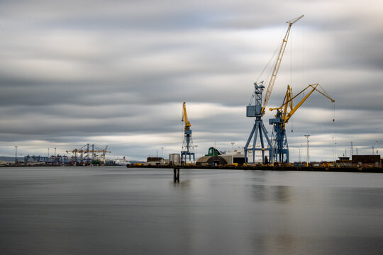 Long  Exposure Photograph Of Cranes In Belfast Harbor, Industrial Shipyard.