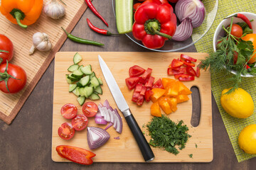 Different vegetables for cooking healthy diet food. Cutting vegetable and greens for salad on wooden board on kitchen