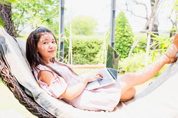 Teenage girl relaxing in hammock using laptop for leisure study. Adolescence, students, high school, technology, lifestyle, youth concept