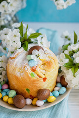 Obraz na płótnie Canvas Traditional cupcake Easter cake kraffin with raisins on blue background. Cherry blossom, choco eggs. Close up of homemade cake. Cruffin with candied fruits. Food. Copy space.