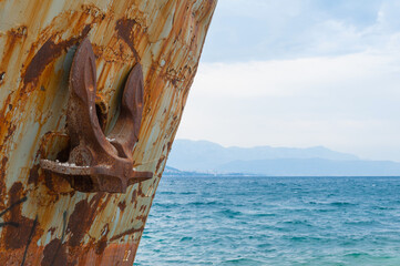 Close-up at the bow with anchor of corroded and abandoned shipwreck washed ashore.