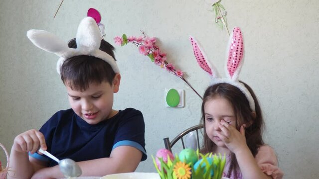 boy and girl are preparing cookies for easter, laughing. Having fun on Easter egg hunt. Child boy and girl wearing bunny ears and painting eggs. colorful eggs