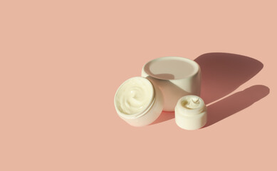 Natural organic cosmetic skin care cream. White bottle and jars with moisturizer on a pink background.Skin care concept