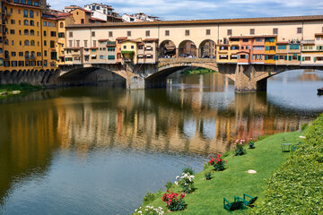 Fototapeta na wymiar A view of Ponte Vecchio on a beautiful sunny spring day with blue sky in Florence, Italy. Popular medieval bridge spanning the Arno river.