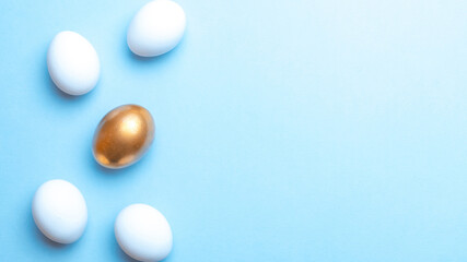 Easter background blue. Golden, white colour egg on pastel blue background in Happy Easter decoration. Flat lay, top view.