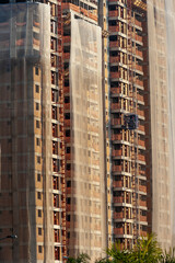 Fototapeta na wymiar Residential building construction site with net protection and outdoor elevator in Sao Paulo city