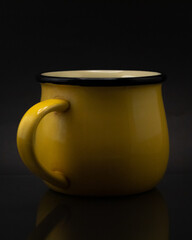 Tasa de metal amarilla con fondo negro.