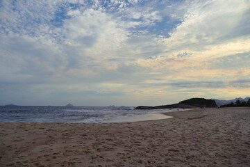 Piratininga Beach, in Niterói in Rio de Janeiro in the late afternoon. Sky with some clouds at the sunset. Sunny day and blue sky with clouds reflecting a lot of yellow and orange