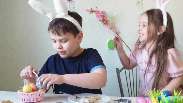 boy and girl are preparing cookies for easter, laughing. Having fun on Easter egg hunt. Child boy and girl wearing bunny ears and painting eggs. colorful eggs