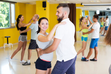 Fototapeta na wymiar Three smiling couples dancing tango in dancing-class