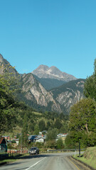 Coche en la carretera con gran vegetaci&oacute;n de fondo.