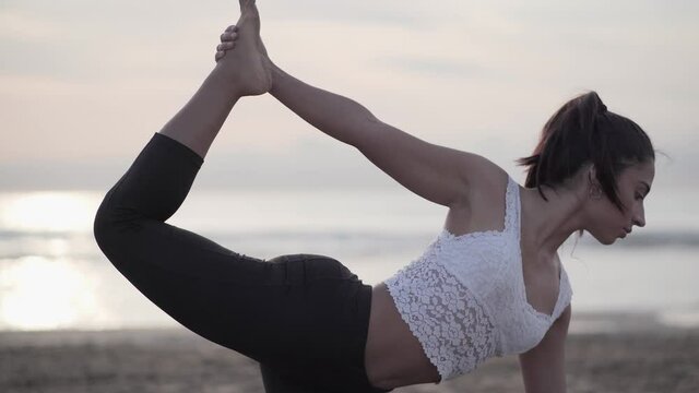 Ardha Dhanurasana - Fit Woman Doing Half Bow Yoga Pose In Beach With Ocean Background. - close up