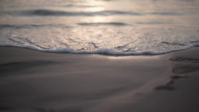 Sunset over the ocean waves on the beach sand - Close up