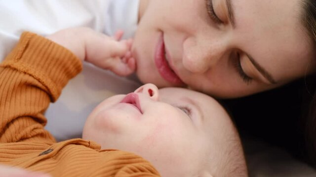 Playful carefree family young mum and cute infant girl enjoy playing touching noses, selective focus of affectionate happy mother embracing pretty baby daughter laughing bonding having fun together