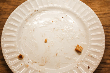 Delicious hot cinnamon roll with icing remnants on a dirty plate