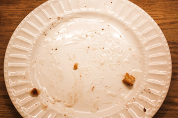Delicious hot cinnamon roll with icing remnants on a dirty plate