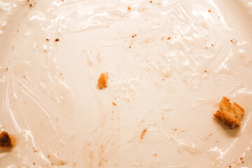 Delicious hot cinnamon roll with icing remnants on a dirty plate