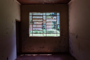 Fototapeta na wymiar Broken window in abandoned dormitory seen from the inside door on the left