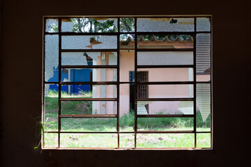 Closeup of a broken window in abandoned during covid 19 pandemics dormitory seen from the inside