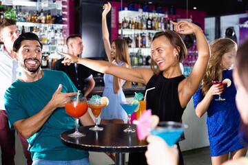 Happy cheerful smiling man with young female are enjoying the party in bar.