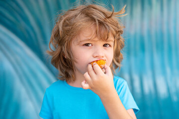Little boy child eating cookies outdoors in sunny summer day. Kids lunch.