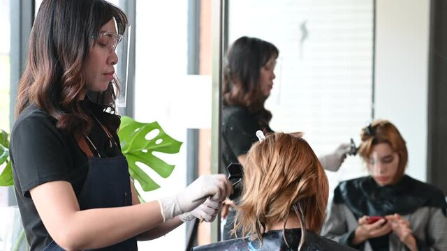 Asian female hairdresser make hairstyles for lady customers in modern beauty salons in Bangkok city.