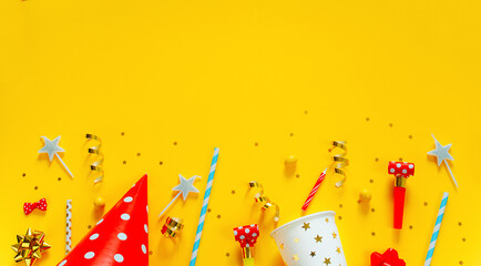 Happy birthday background: party hat, serpentine, stars, cocktail tubes, candles, blower on a yellow background.