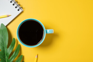 Blue coffee cup on yellow background top view. Summer concept.