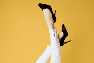 Women's inverted legs and black shoes white jeans isolated yellow background