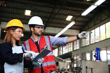 Suppervisor and engineer wearing safety unform and equipment disucsion at work shop or factory