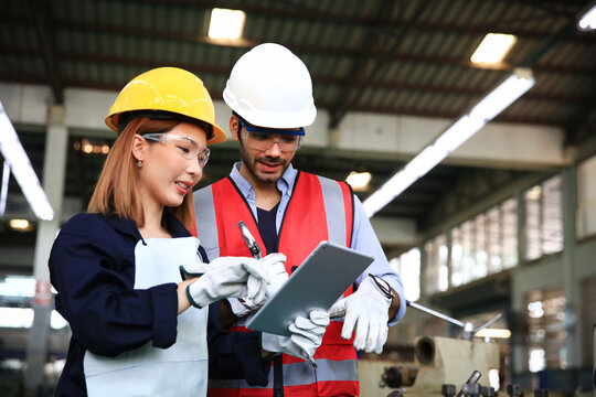 Supervisor and engineer wearing safety unform and equipment disucsion at work shop or factory