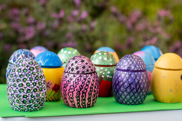 Hand-made Easter eggs on a green pedastal in front of purple lavender flowers.