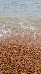Seashore with red pebbles and water