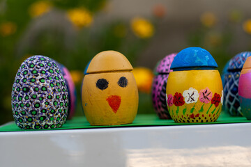 Hand-made Easter eggs on a green pedastal in front of yellow and orange spring flowers