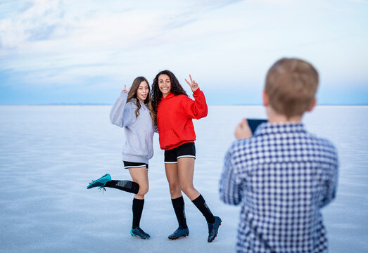 Two playful teenage girls posing for a cell phone photo at the Bonneville salt flats