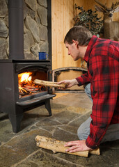 man loading wood in woodburning stove