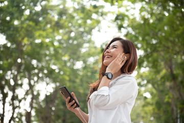 Thai women of Asian descent use a smartphone on the street on a sunny summer day.