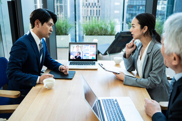 都心の企業で働くビジネスチームがオンライン会議を行っている