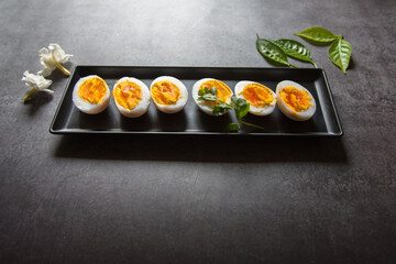 Close up of slices of boiled eggs arranged on a black tray with use of selective focus.