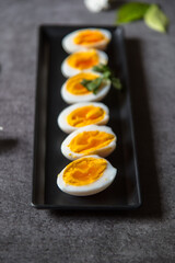 Healthy food item slices of boiled eggs arranged on a black tray with use of selective focus.
