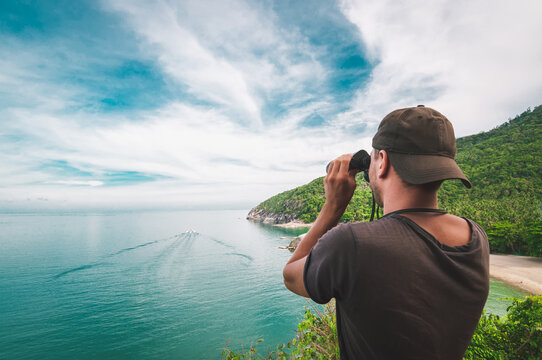 Man with binoculars inspects the beautiful nature around him, Koh Phangan, Thailand