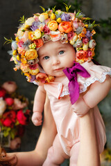 Portrait of a baby in a flower cap. A beautiful baby of 6 months in a hat made of flowers, a small child in a flower wreath.