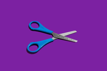 steel office scissors on a purple surface