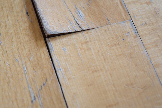 old parquet or laminate flooring deformed by water exposure. scratched floor covering close-up